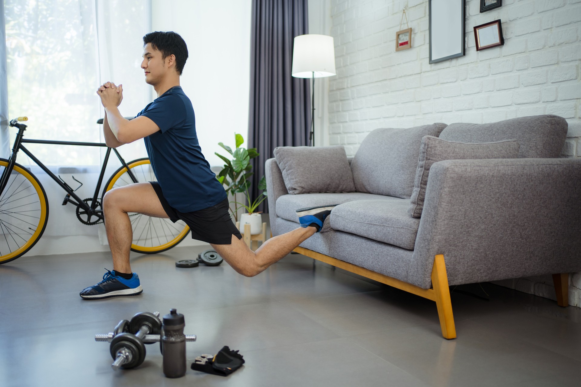 Active young man watching online training video on laptop. He's stretching during his morning workout at home.